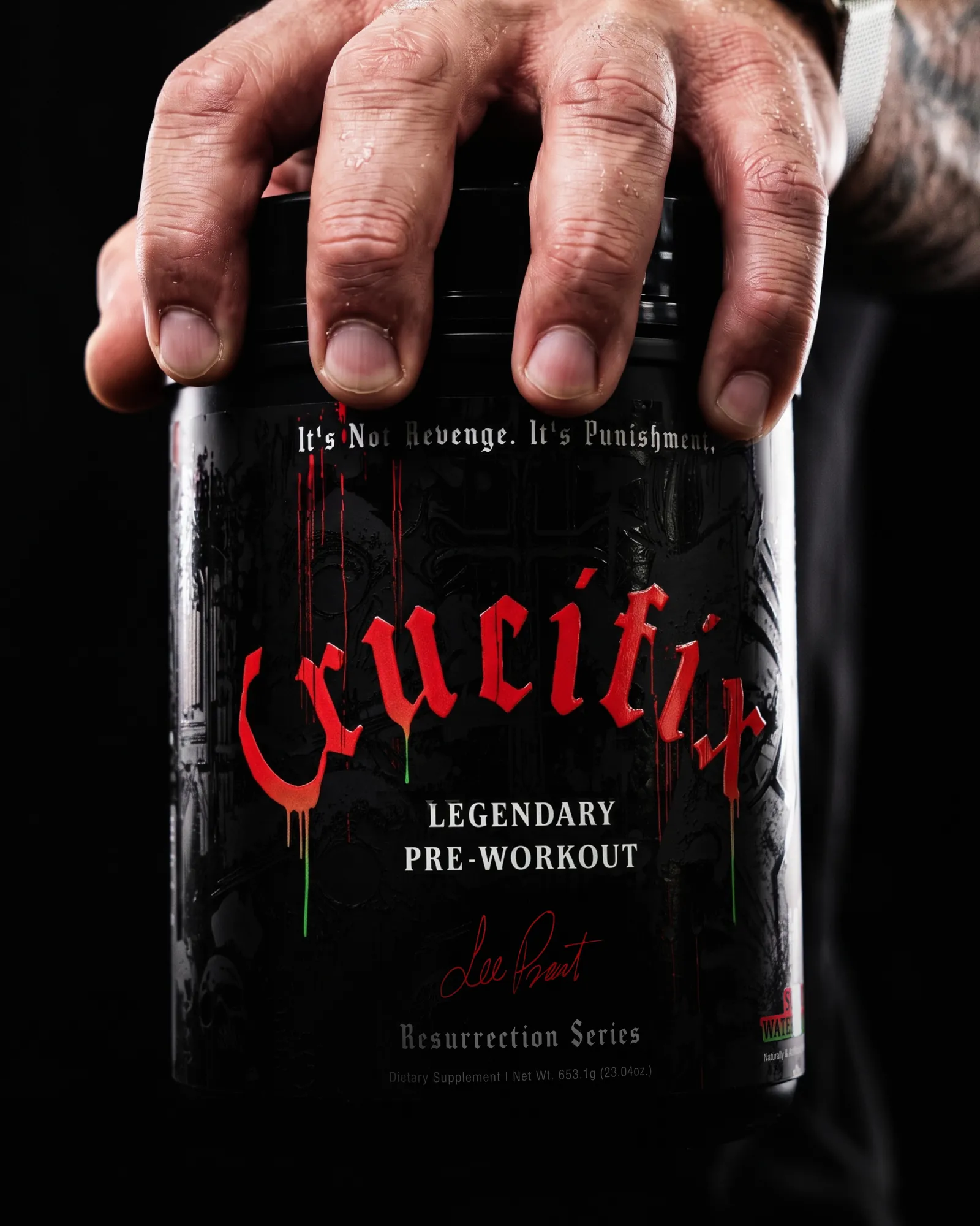 Close-up of a hand gripping a black NutriFitt Crucifix tub; the label reads It's Not Revenge. It's Punishment.