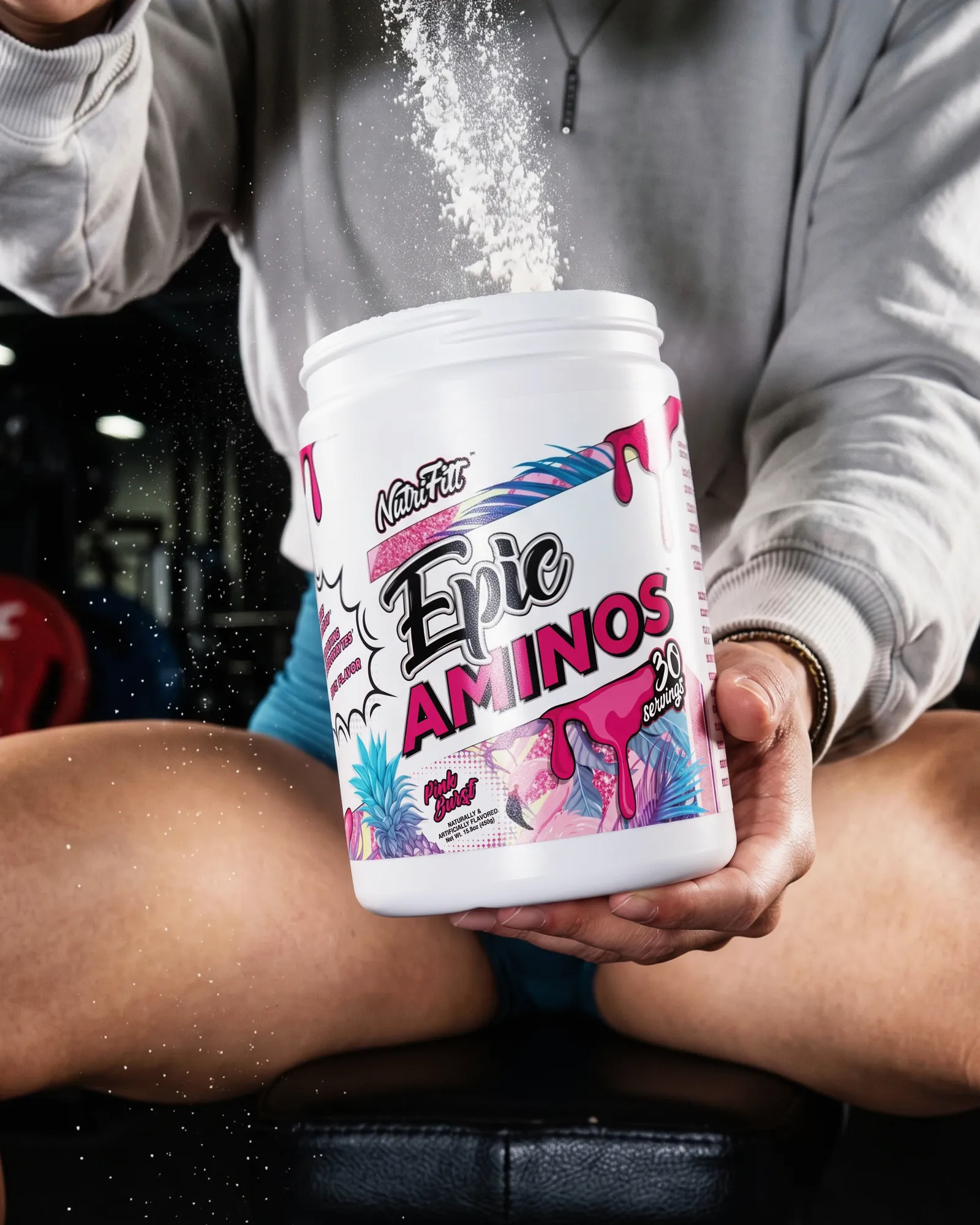 Close-up of powder falling into an open NutriFitt Epic Aminos tub held in both hands.