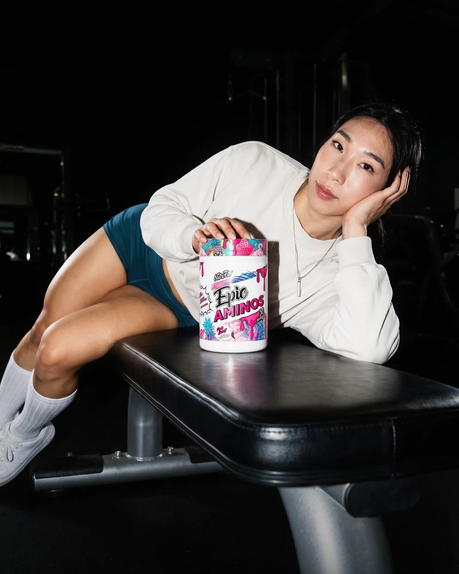 Athlete leaning over a gym bench with her hand resting on a NutriFitt Epic Aminos tub.