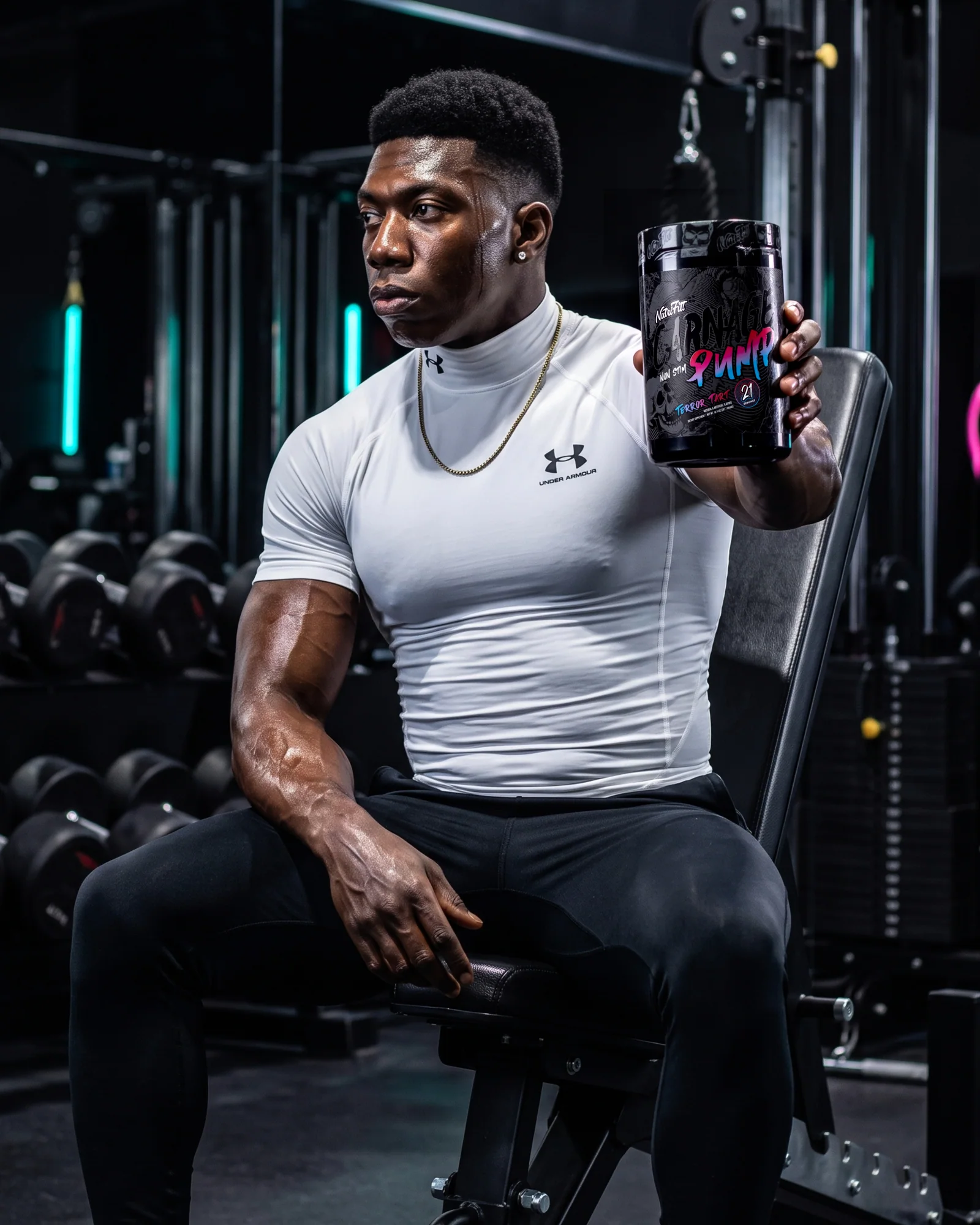 Muscular athlete seated in a dark gym holding NutriFitt Carnage Pump Terror Tart.