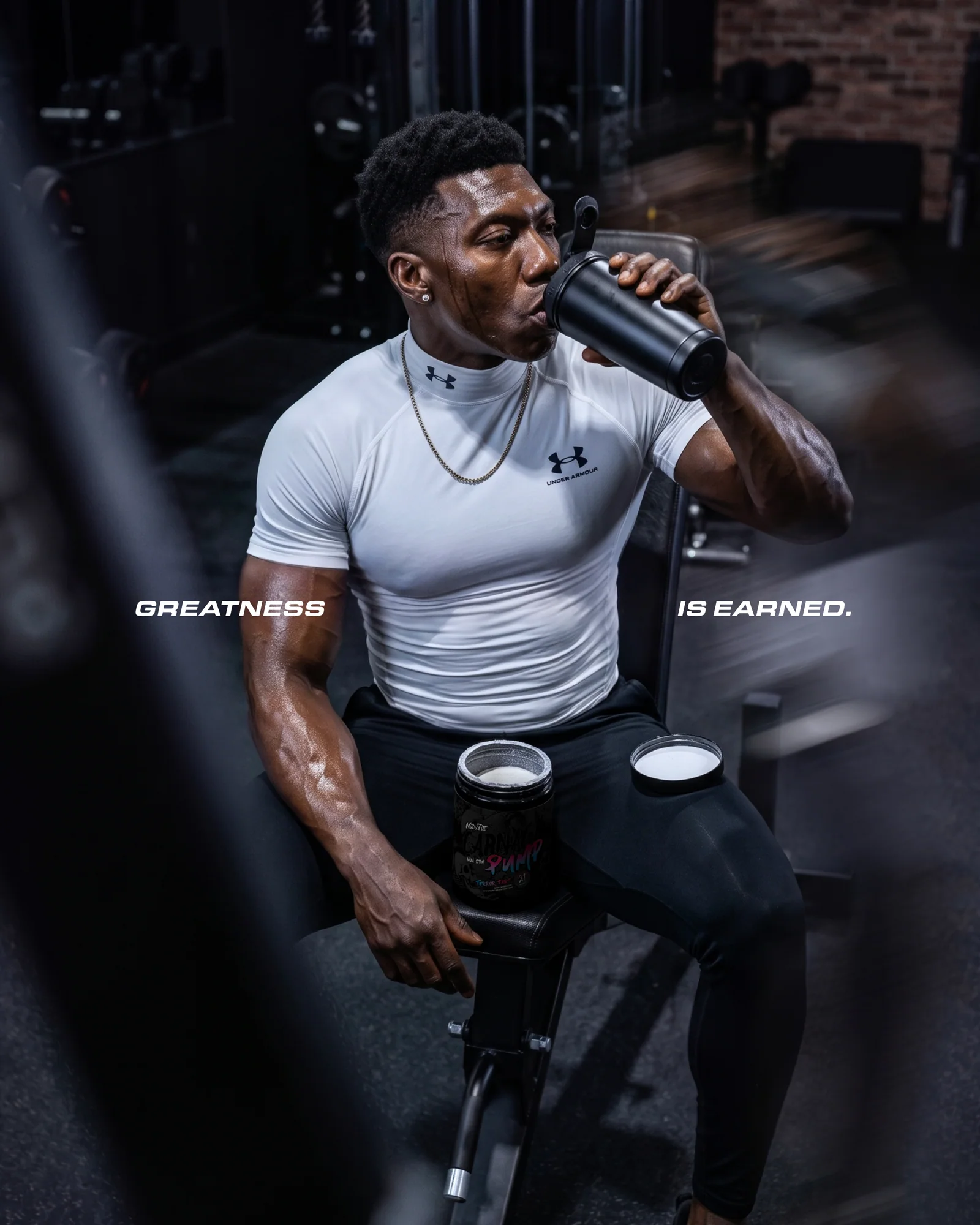 Athlete drinking from a shaker beside an open NutriFitt Carnage Pump tub; text reads Greatness is earned.