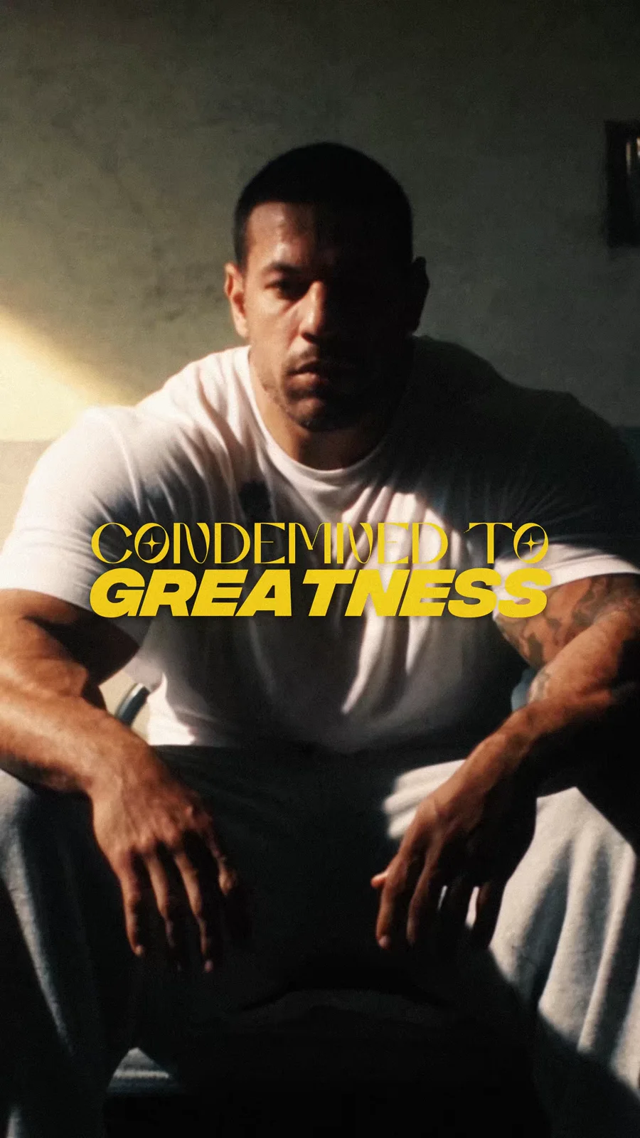 An athlete seated in a shadowed room beneath the Condemned to Greatness title.