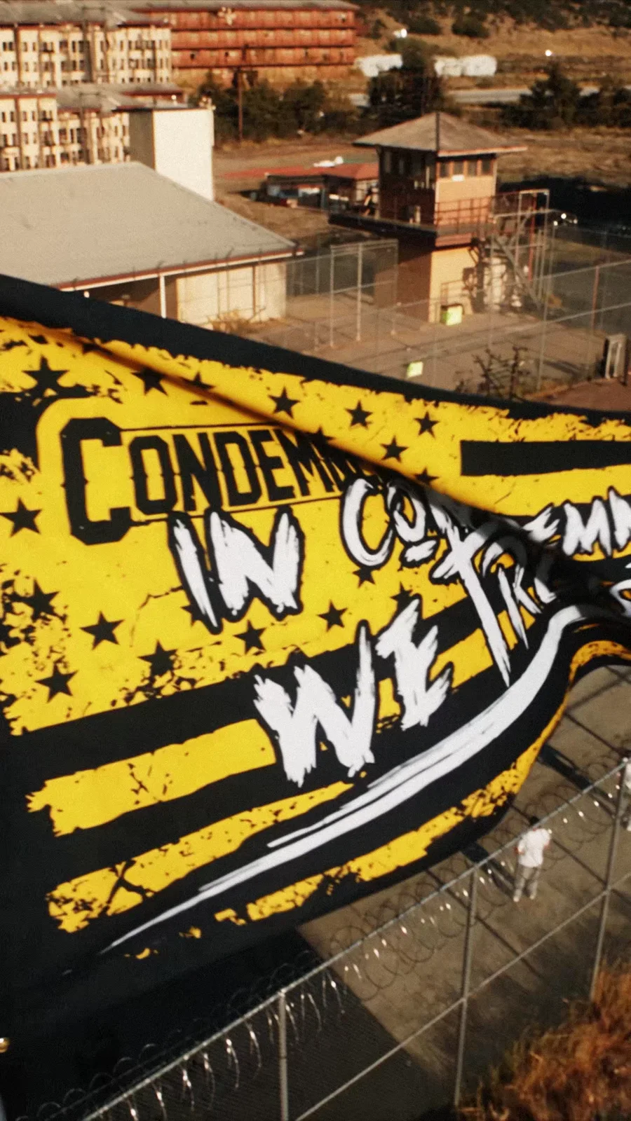 A yellow Condemned flag overlooks the prison-yard setting.