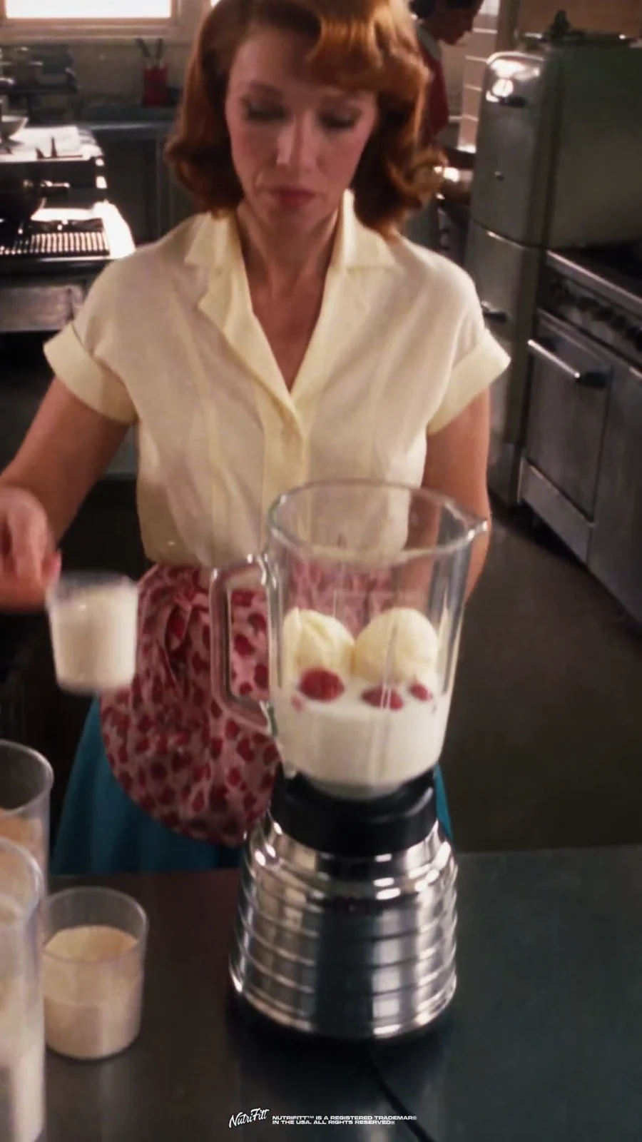 Diner waitress builds the strawberry and vanilla milkshake base inside a chrome blender.