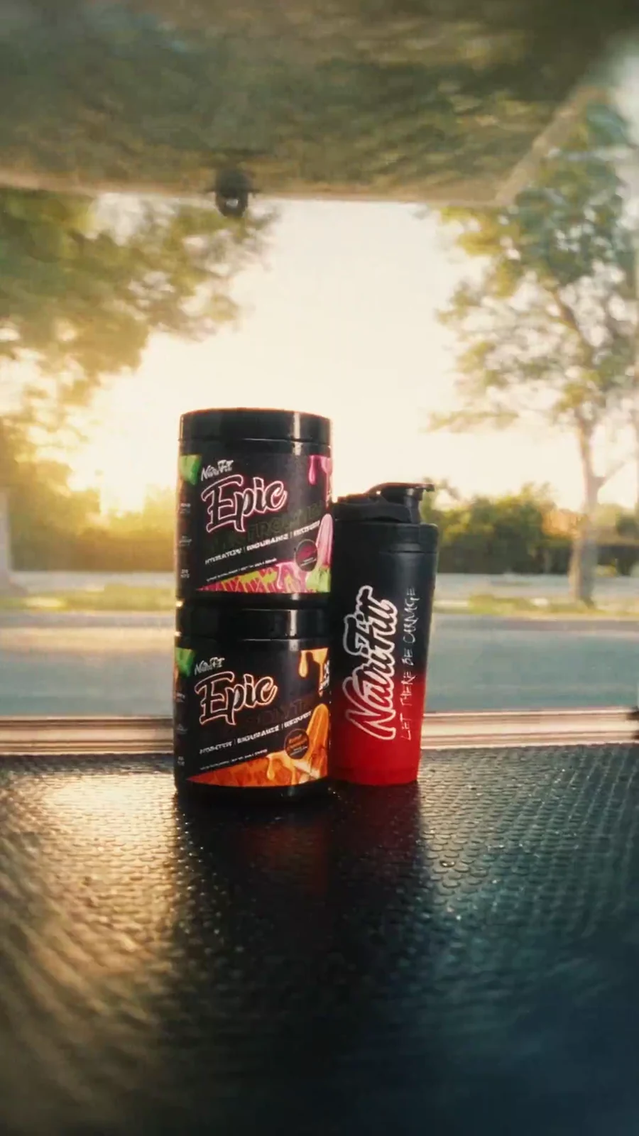 Epic watermelon and mango tubs stand with a branded shaker on the serving counter in warm light.