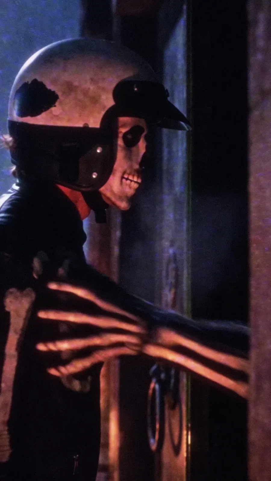 A skeletal hand reaches out of a dark mausoleum doorway and grabs the helmeted courier.