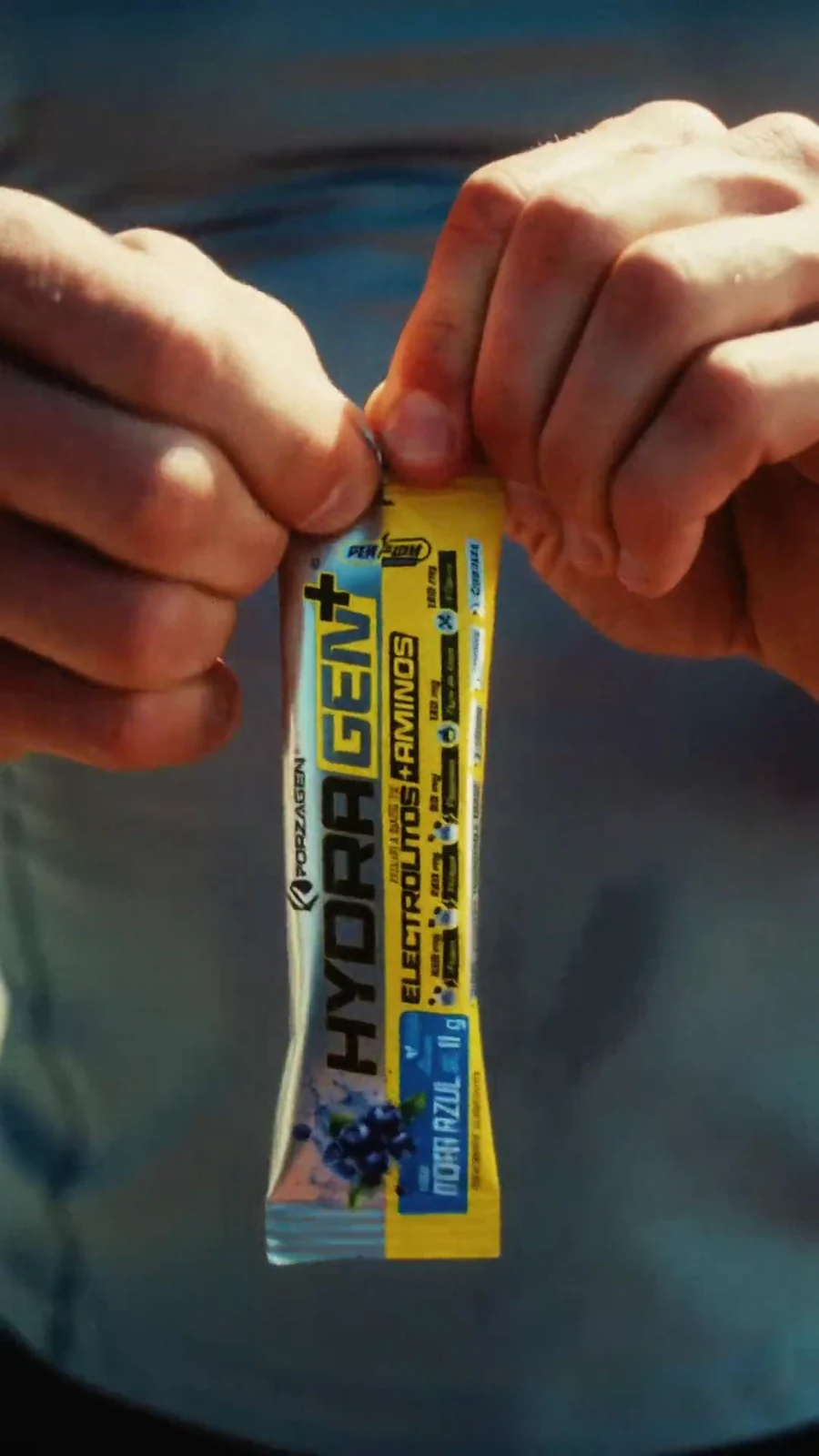 Hands tear open a yellow Forzagen Hydragen electrolyte sachet in tight close-up.