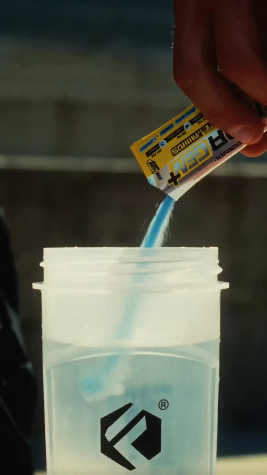 Blue electrolyte powder pours from a Hydragen sachet into a clear Forzagen shaker.