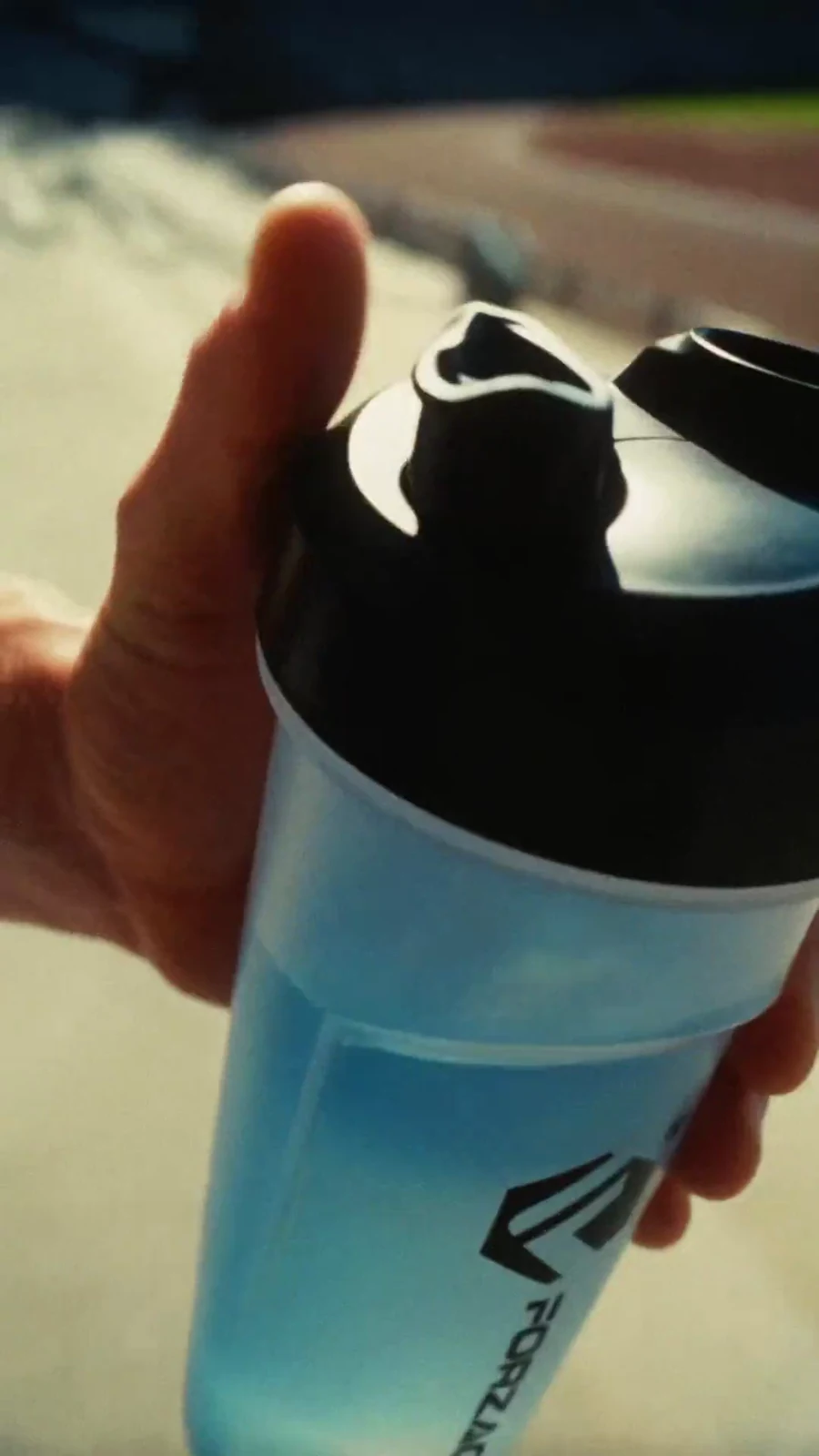 Athlete secures the black lid on a clear Forzagen shaker after mixing Hydragen.