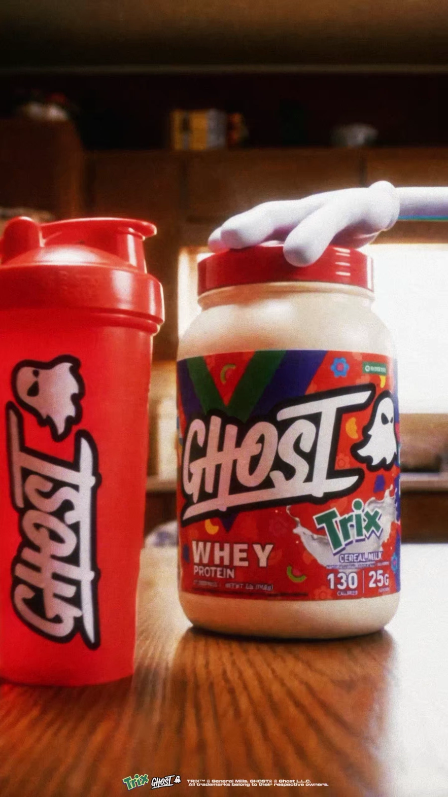 Ghost x Trix whey tub and red shaker on a sunlit kitchen table.