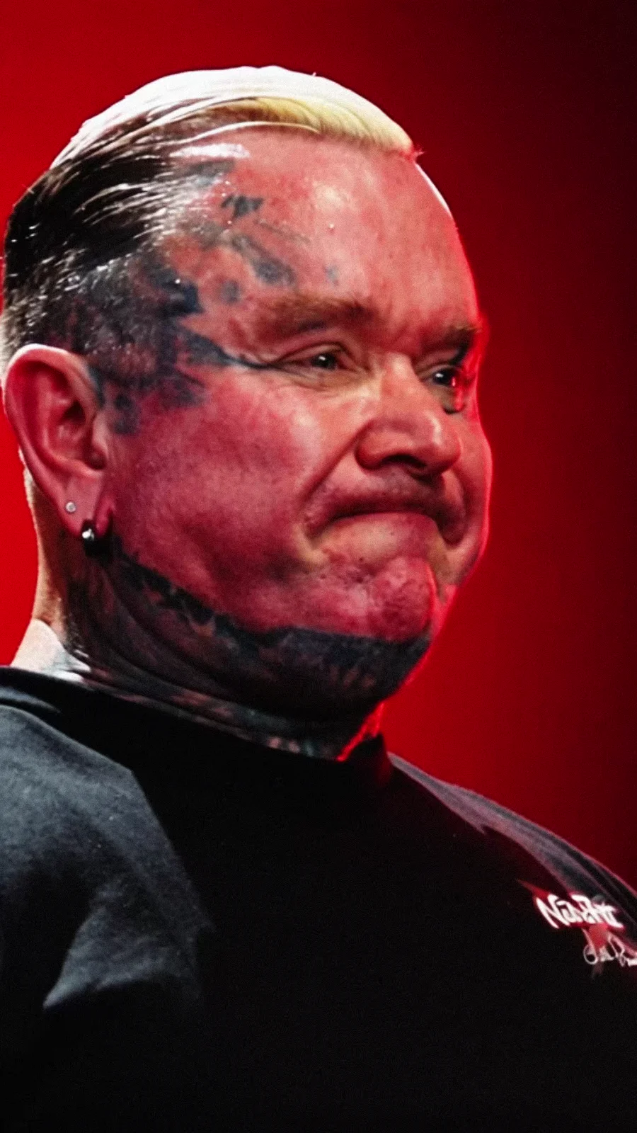 Close portrait of Lee Priest with red light across his face.
