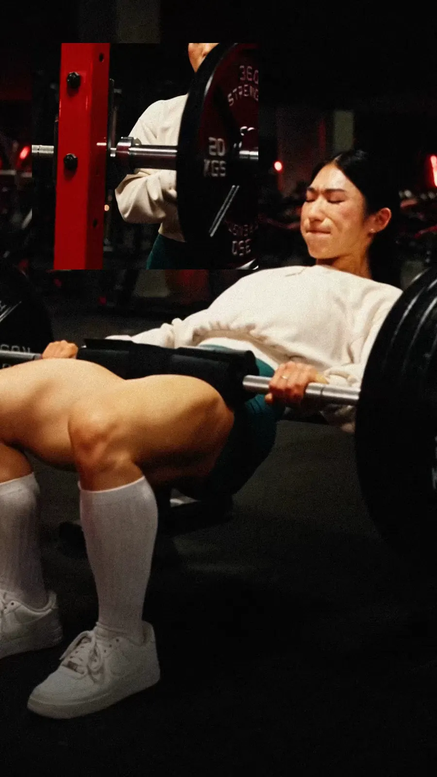 The athlete drives a heavy barbell hip thrust in the gym, jaw clenched.