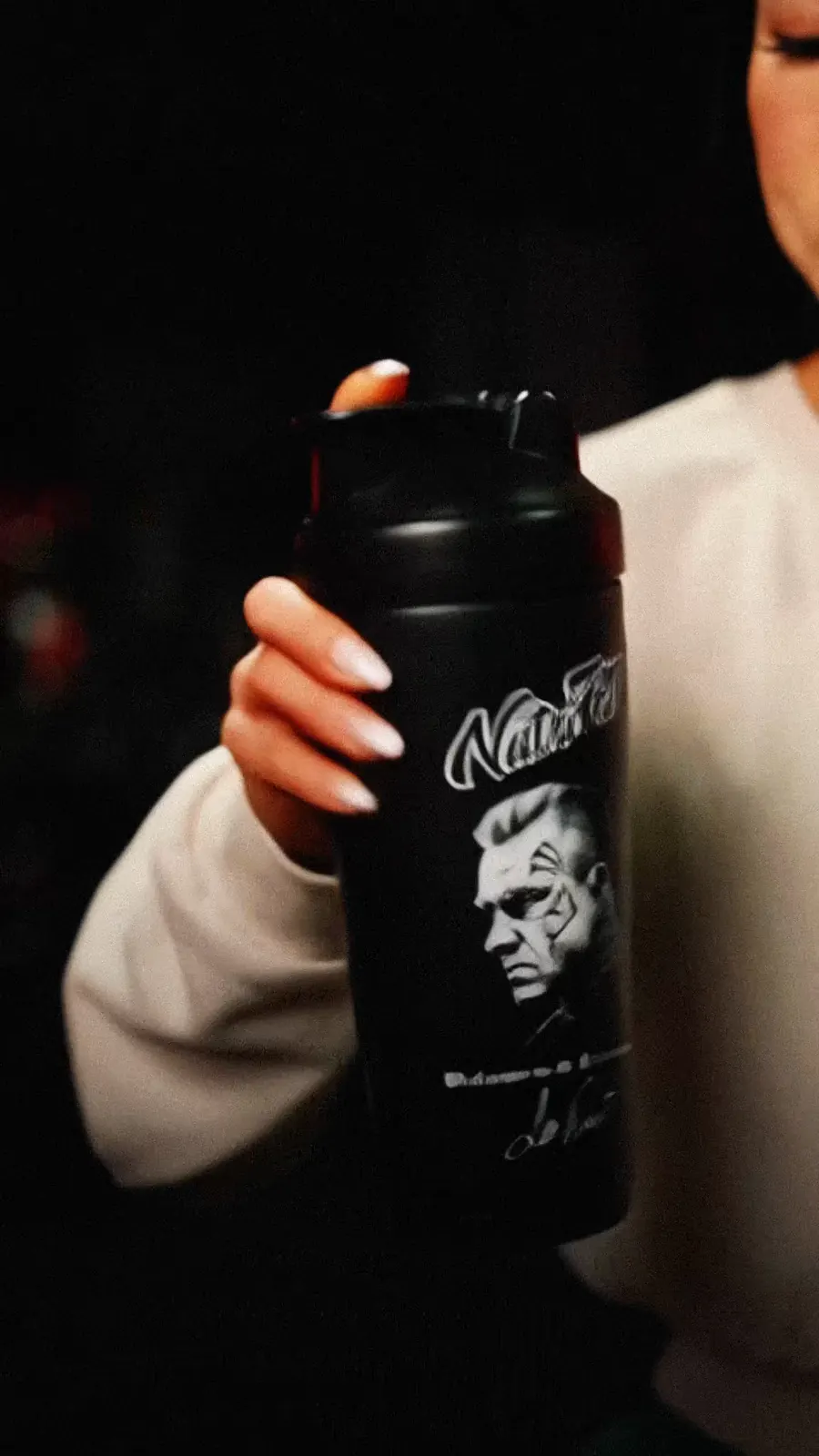 The athlete holds a black NutriFitt shaker.