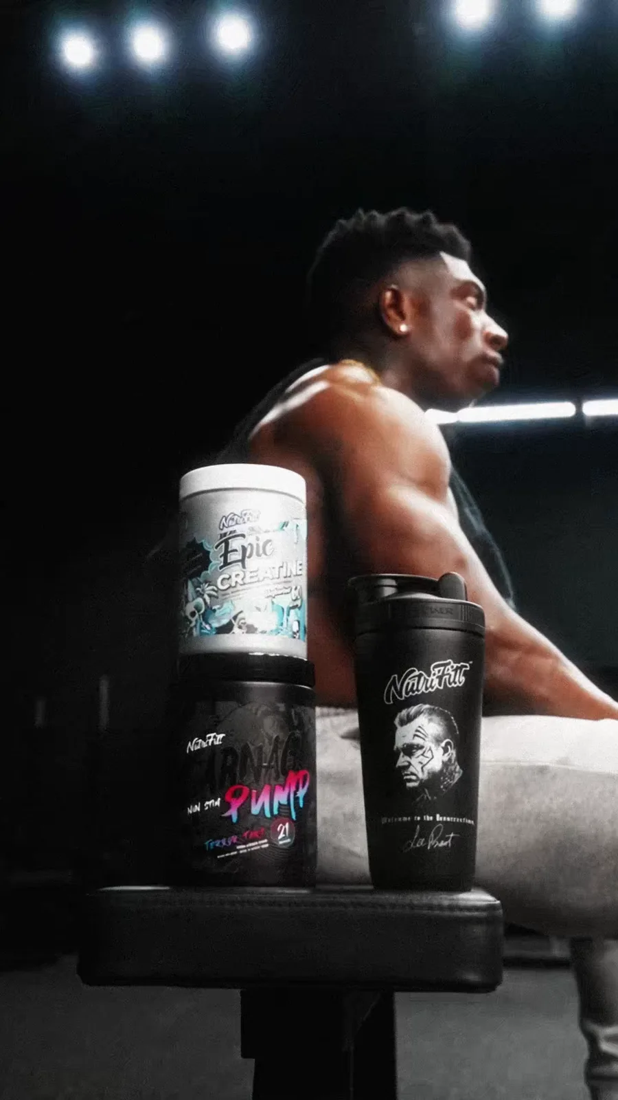 NutriFitt Epic Creatine, Pump and shaker stand in the foreground as TheOneCay rests beneath gym lights.