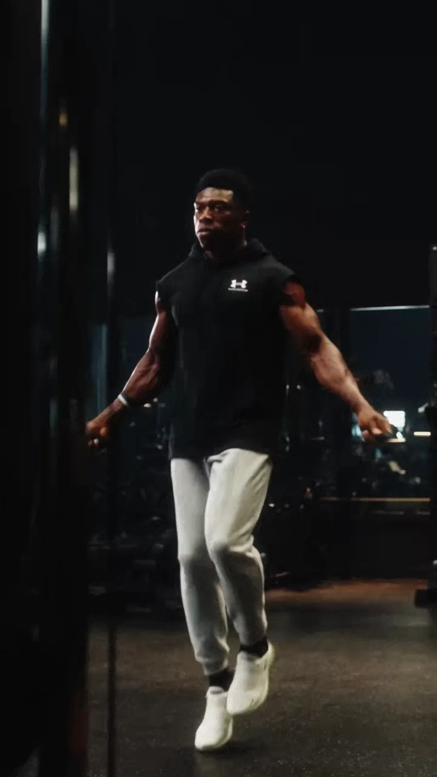 TheOneCay skips rope in a dark gym between narrow vertical reflections.