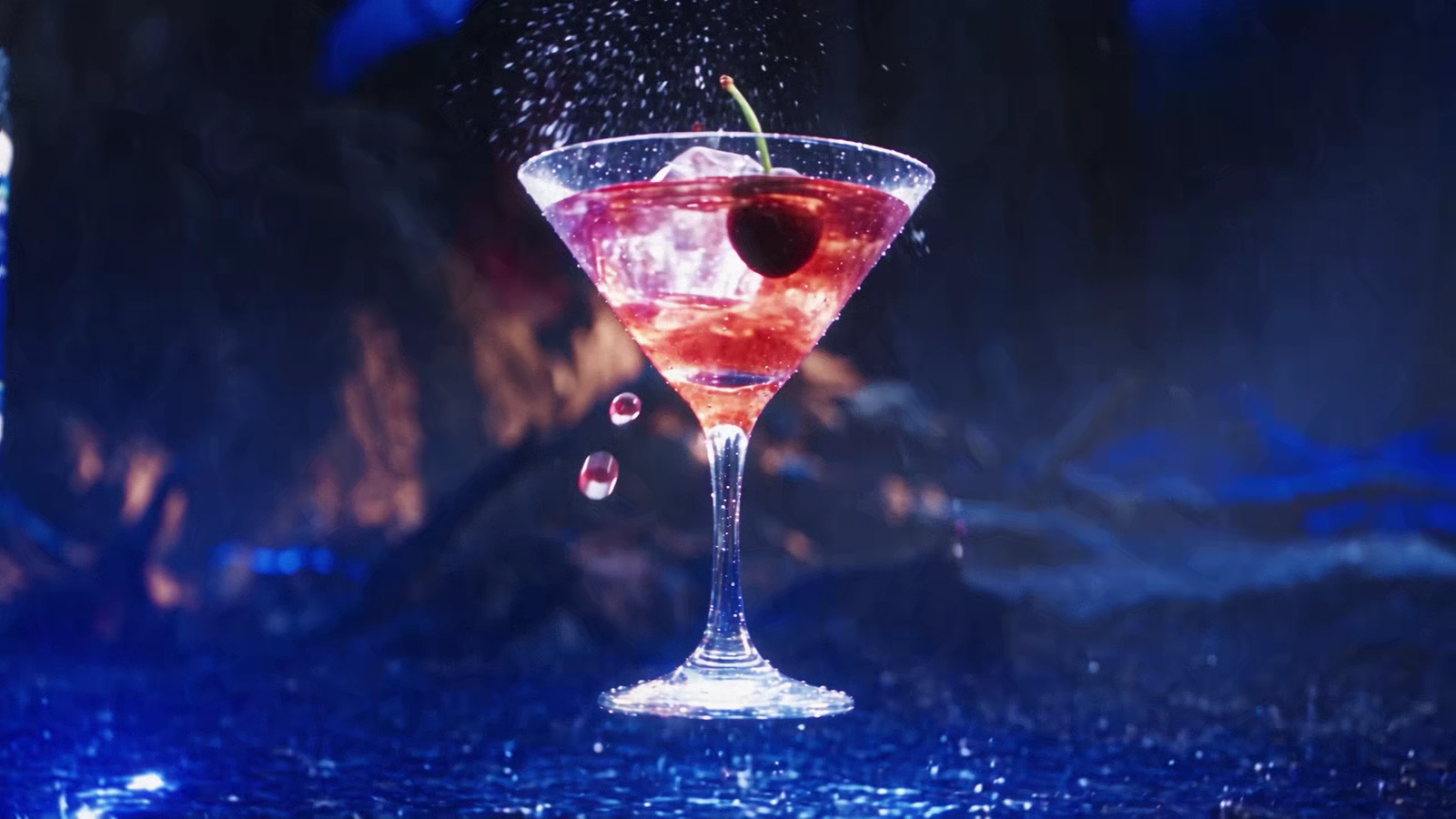 Cherry cocktail suspended above a wet reflective forest floor with red and blue light.