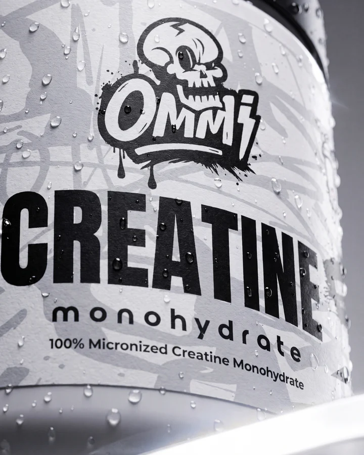 Water droplets cover the front of an Ommi Creatine Monohydrate tub in an extreme product macro.