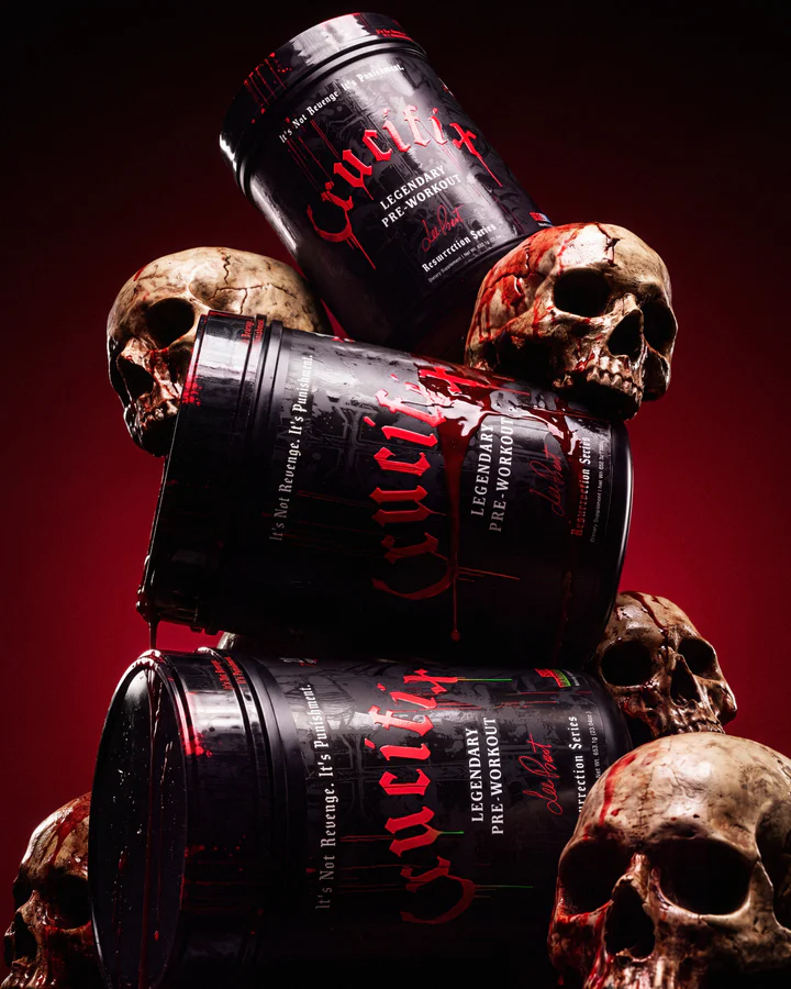 Tower of black Crucifix pre-workout tubs rises between weathered skulls on a dark red-lit set.