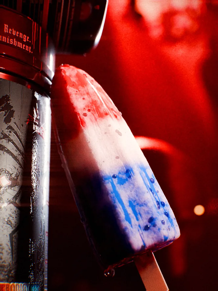 Macro of a melting red, white and blue popsicle leaning on the black Crucifix tub in red light.