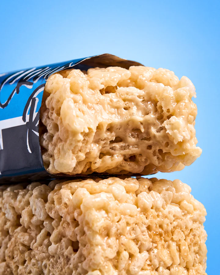 Macro view of two glossy rice-crisp snack pieces beside a partially visible blue Crunchy Rice wrapper.