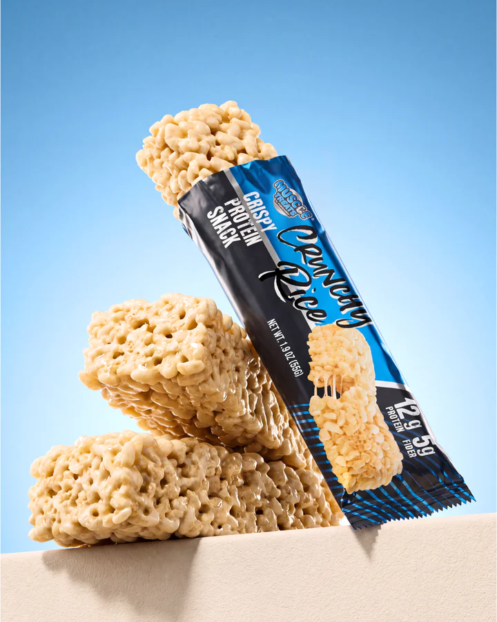 An upright Crunchy Rice wrapper leans between large rice-crisp snack pieces on a cream-and-blue set.