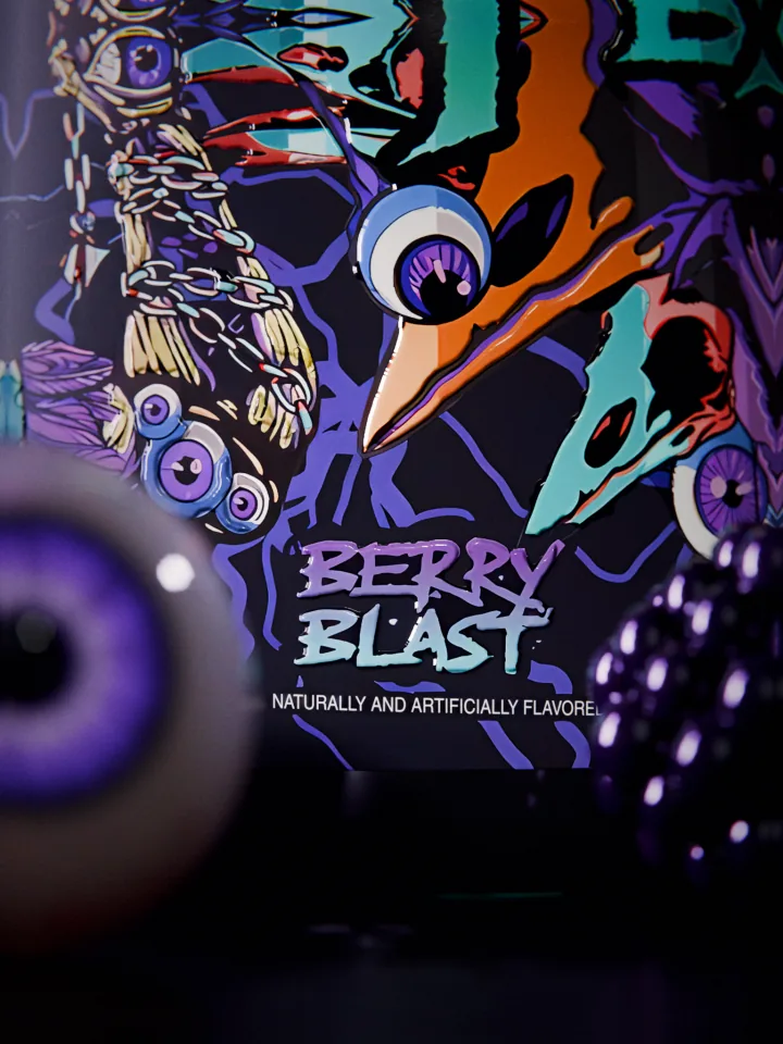 Macro of the Berry Blast flavor name on the FLAME label with a blurred purple-eyed eyeball close to the lens on the left and a blackberry on the right.