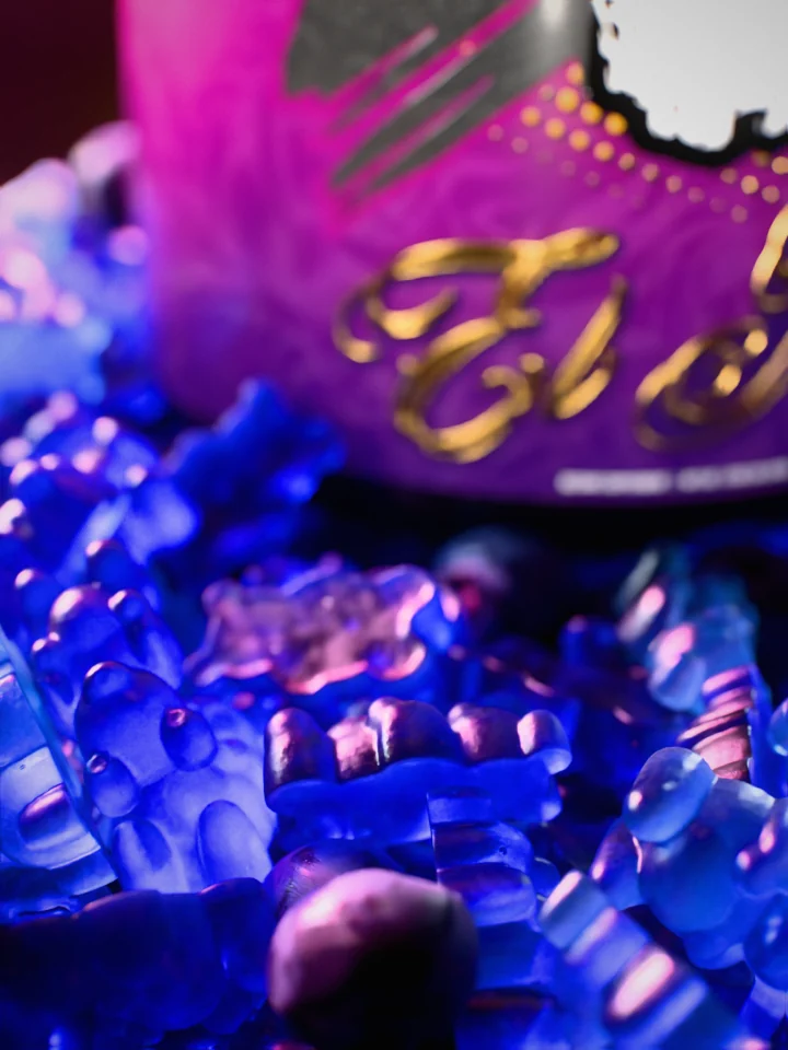 Macro of translucent blue gummy bears and blueberries with the El Jefe Neuro tub out of focus behind.