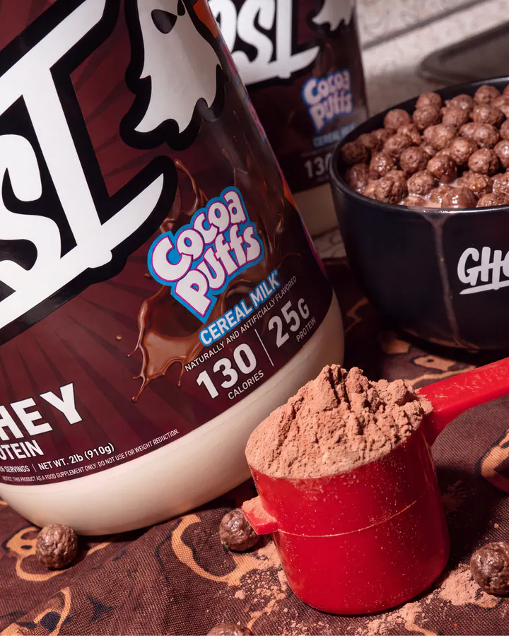 Close product view of Ghost Cocoa Puffs whey, chocolate cereal and a red scoop filled with protein powder.