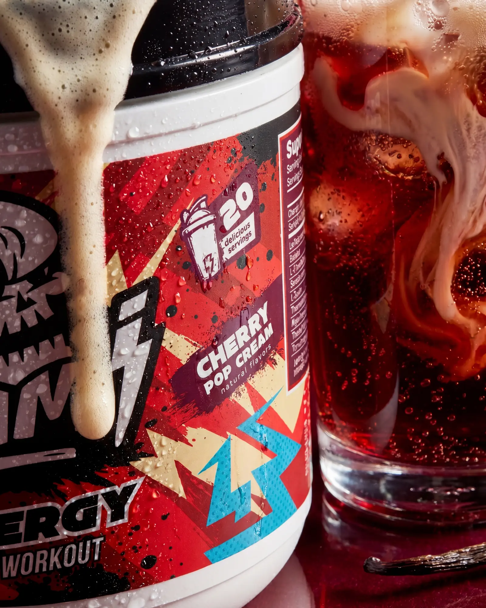 Ommi Energy Cherry Pop Cream pre-workout tub beside a red iced drink and creamy texture.