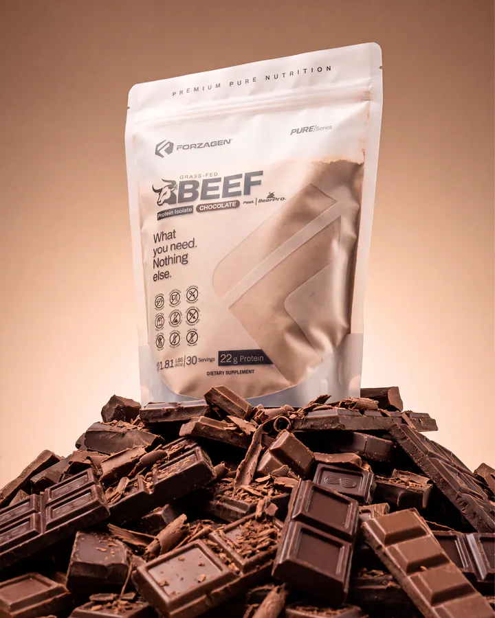 Pure Beef Chocolate protein bag rising from a pile of dark chocolate pieces.