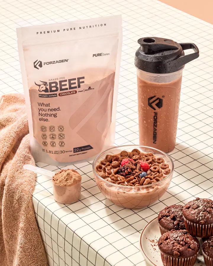 Pure Beef Chocolate protein bag and shaker arranged with cereal, brownies and chocolate powder.